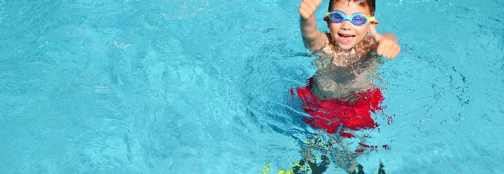 Kind mit Taucherbrille und Flossen im Schwimmbad